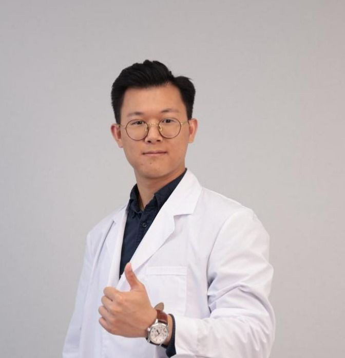 Person wearing a white lab coat giving a thumbs-up gesture.