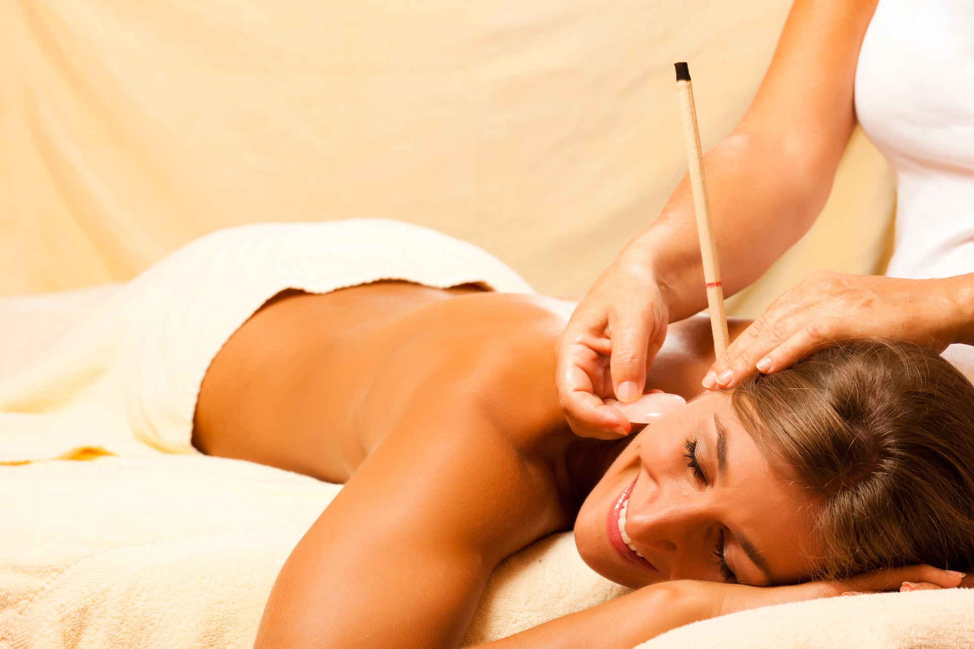 Woman with ear candles and gem massage